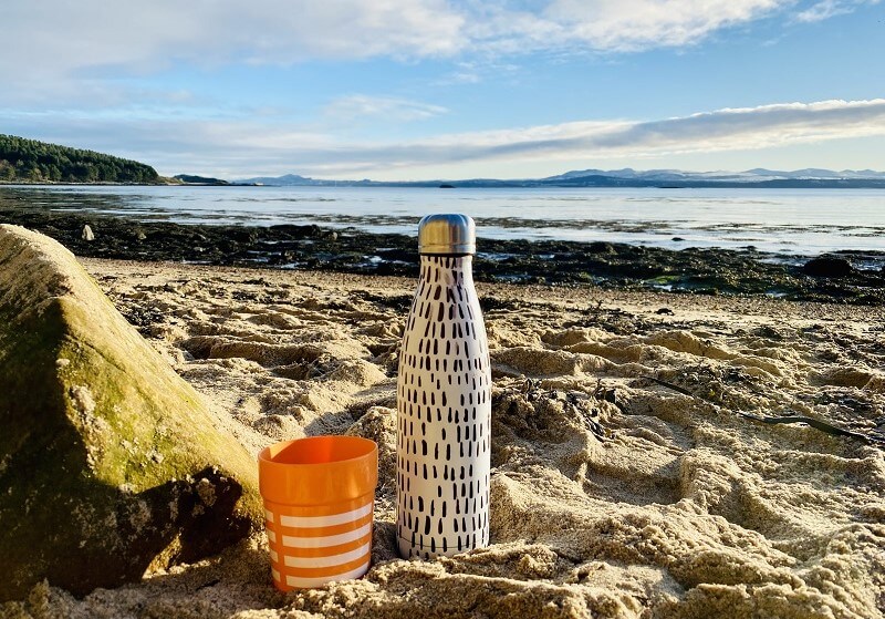 Flask in the sand on a beach